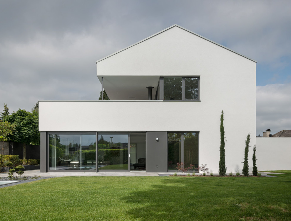 Пример оригинального дизайна: двухэтажный, белый дом среднего размера в стиле модернизм с двускатной крышей