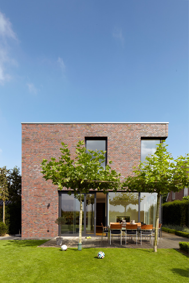 Idée de décoration pour une grande façade de maison marron minimaliste en brique à un étage avec un toit plat.