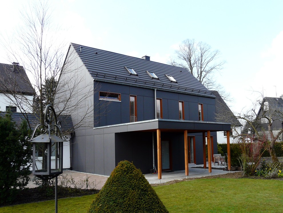 Imagen de fachada de casa negra moderna de dos plantas con tejado de teja de barro