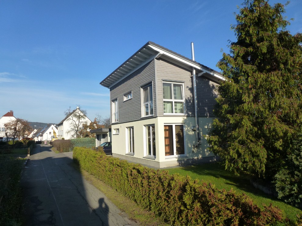 Kleines, Zweistöckiges Modernes Haus mit Mix-Fassade, grauer Fassadenfarbe, Pultdach und Ziegeldach in Sonstige