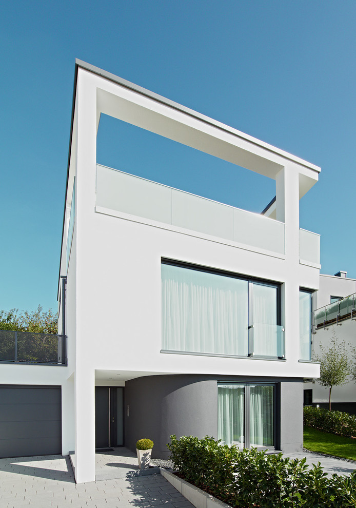 Пример оригинального дизайна: трехэтажный, белый дом среднего размера в современном стиле с плоской крышей