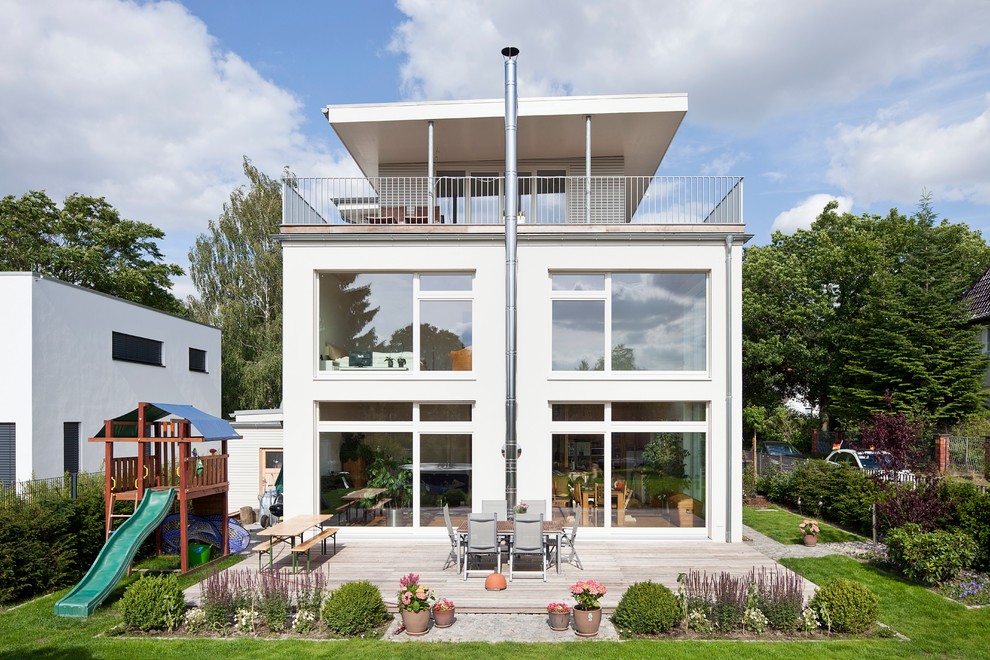Exempel på ett mellanstort modernt vitt hus, med tre eller fler plan, platt tak och stuckatur