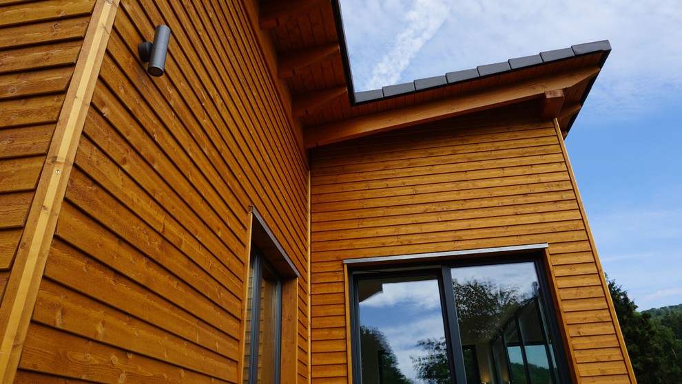 Esempio della casa con tetto a falda unica piccolo marrone classico a un piano con rivestimento in legno e copertura in tegole