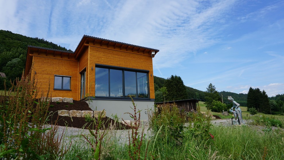 Идея дизайна: деревянный, маленький, одноэтажный, коричневый дом в классическом стиле с односкатной крышей и черепичной крышей для на участке и в саду