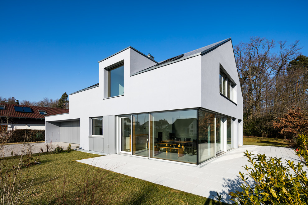 Источник вдохновения для домашнего уюта: двухэтажный, серый частный загородный дом среднего размера в стиле модернизм с облицовкой из цементной штукатурки и двускатной крышей