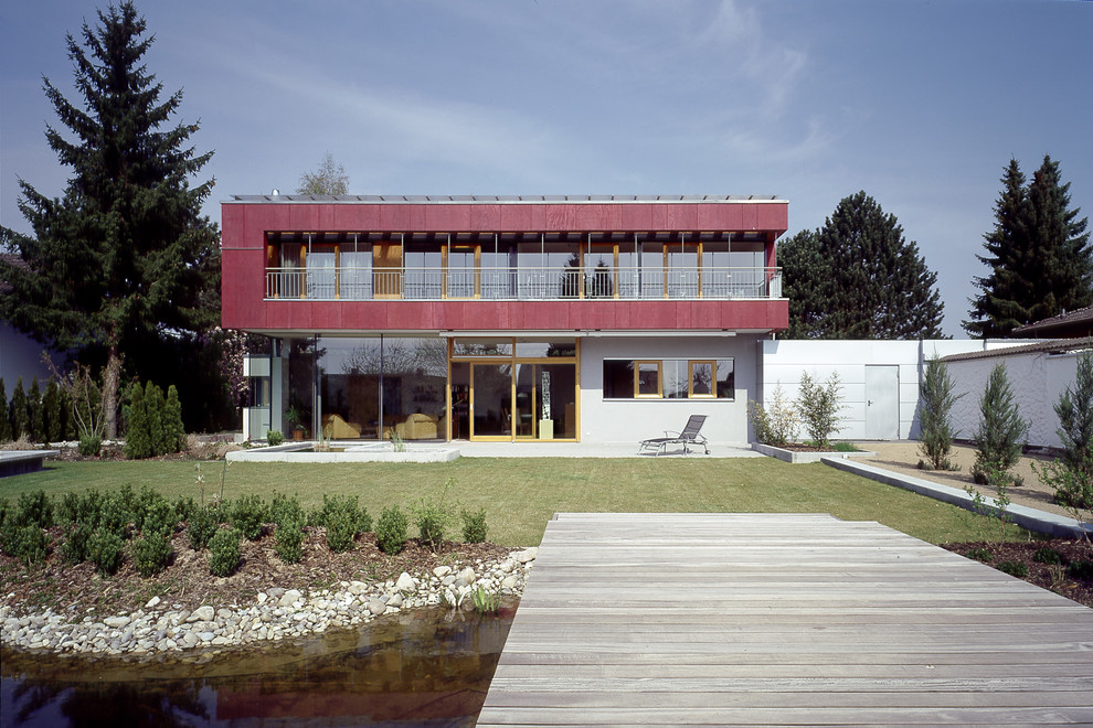 Imagen de fachada roja actual grande de dos plantas con tejado plano