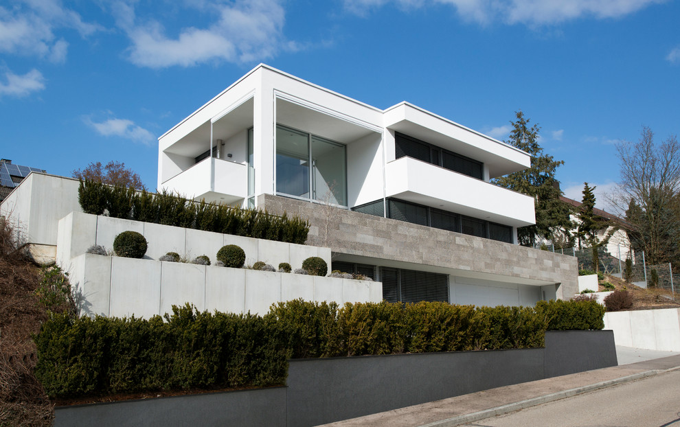 Modelo de fachada blanca minimalista grande de tres plantas con tejado plano