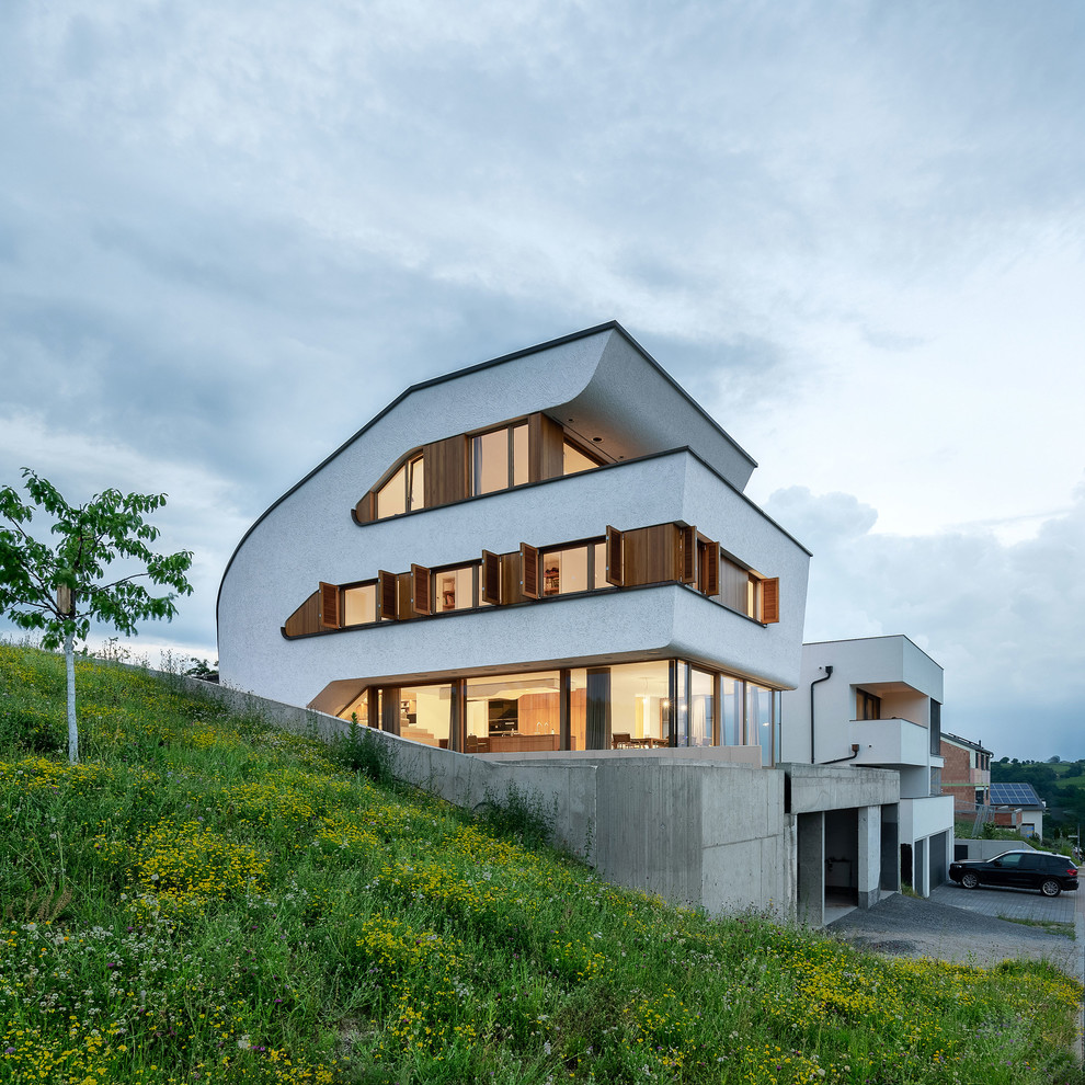 Идея дизайна: огромный, белый частный загородный дом в современном стиле с разными уровнями, облицовкой из цементной штукатурки, односкатной крышей и зеленой крышей