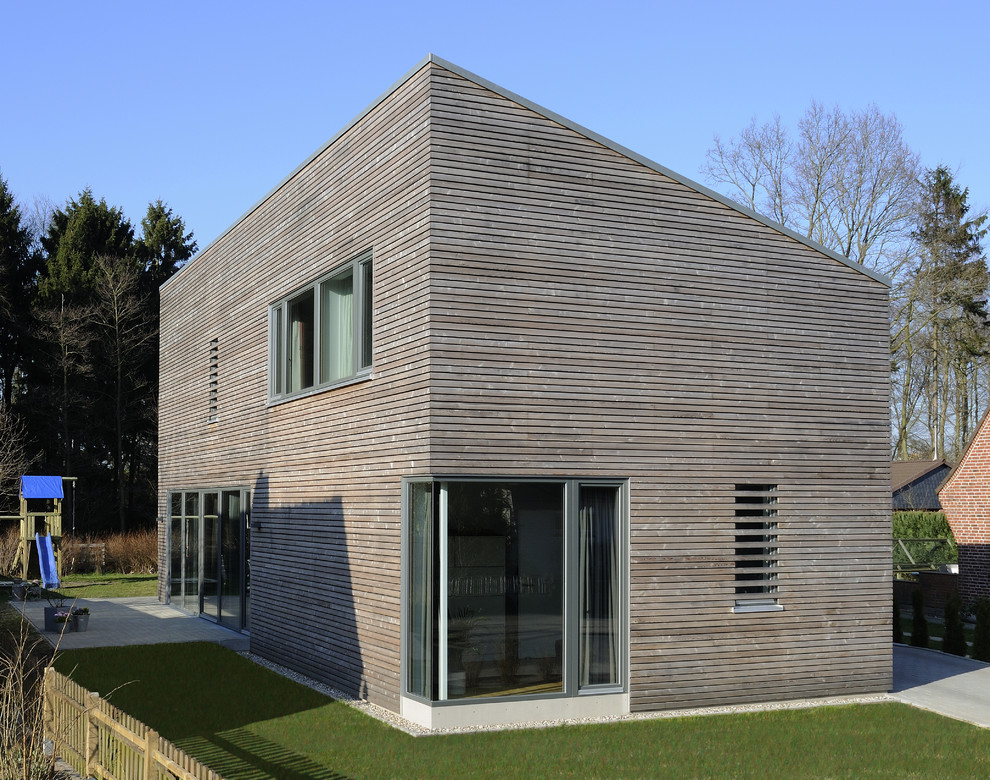 Idée de décoration pour une façade de maison marron design en bois de taille moyenne et à un étage avec un toit en appentis.