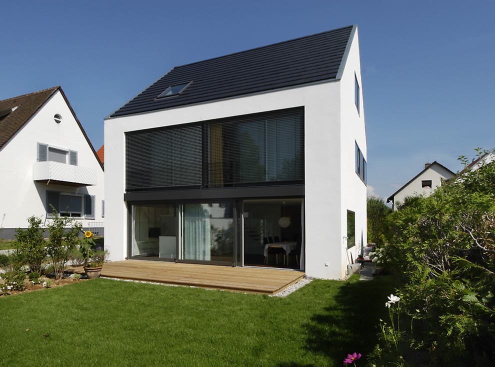 На фото: трехэтажный, белый дом среднего размера в современном стиле с облицовкой из цементной штукатурки и двускатной крышей с