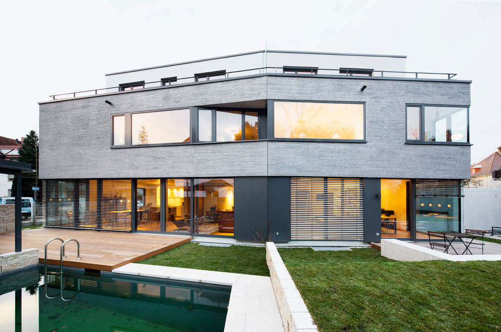 Modern inredning av ett stort grått hus, med tre eller fler plan, blandad fasad och platt tak