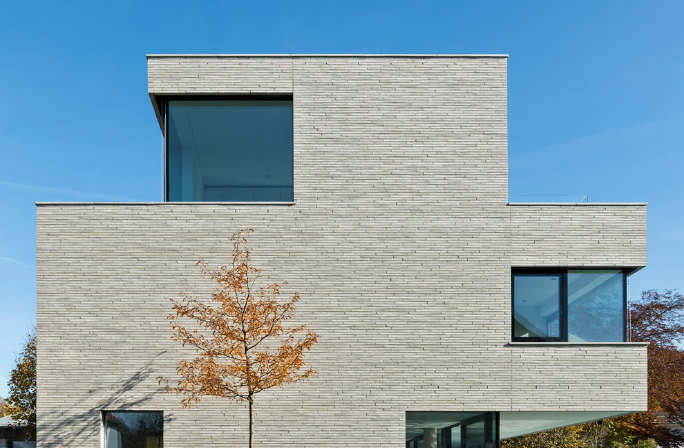 Immagine della villa grande beige moderna a tre piani con tetto piano