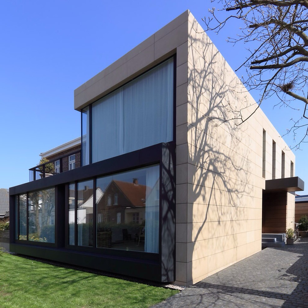 Mittelgroßes, Zweistöckiges Modernes Haus mit Steinfassade, beiger Fassadenfarbe und Flachdach in Sonstige