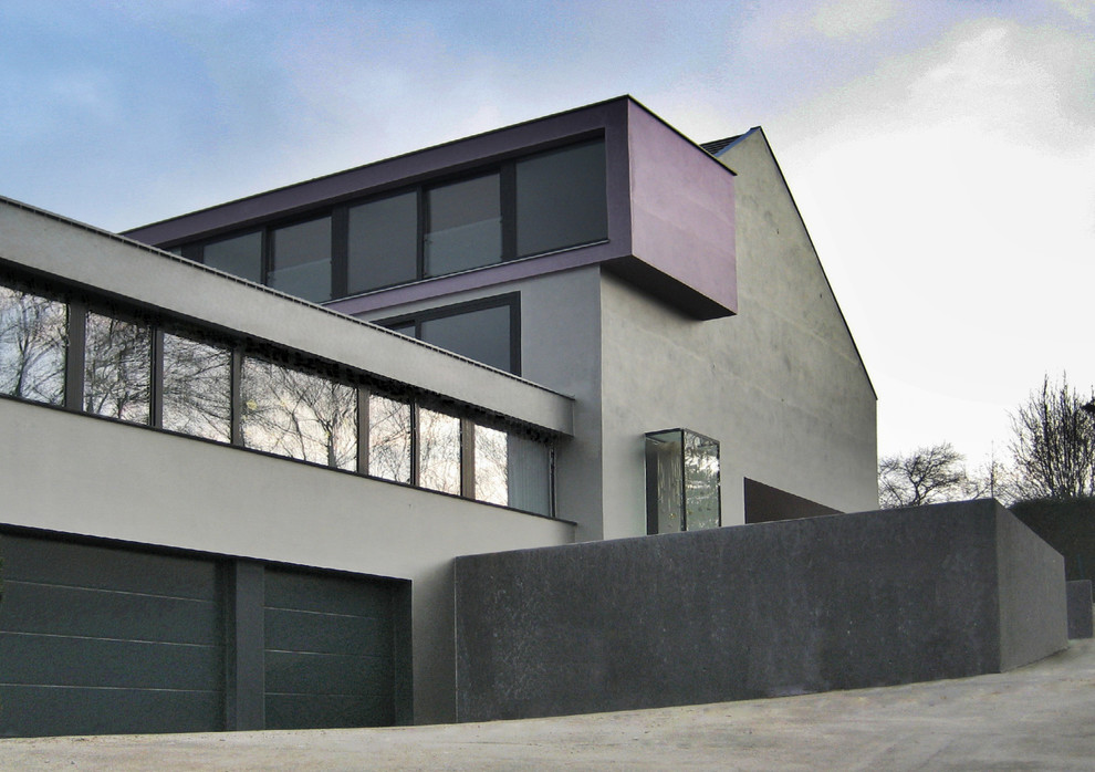 Immagine della facciata di una casa grigia contemporanea a tre piani di medie dimensioni con tetto a capanna e rivestimento in cemento