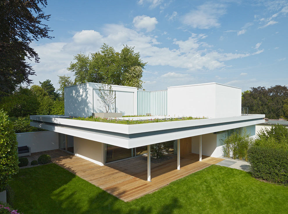 Свежая идея для дизайна: двухэтажный, белый дом среднего размера в стиле модернизм с плоской крышей и облицовкой из цементной штукатурки - отличное фото интерьера