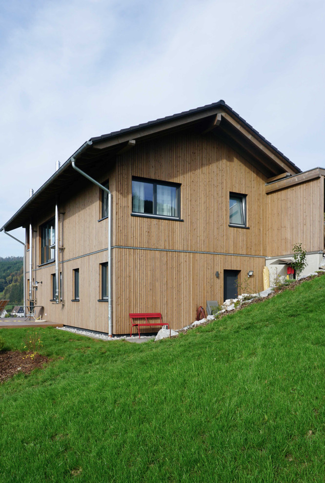 Ejemplo de fachada de casa marrón campestre de dos plantas con revestimiento de madera y tejado a dos aguas
