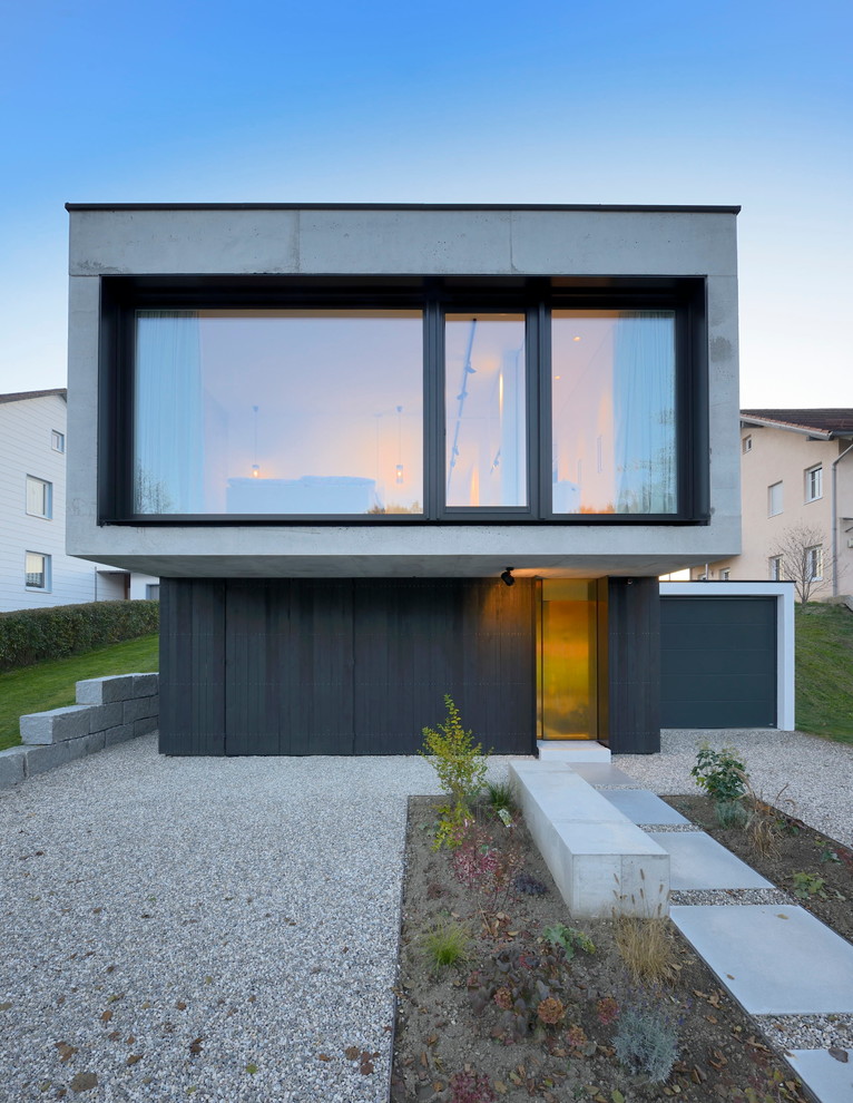 На фото: одноэтажный, черный дом среднего размера в стиле модернизм с облицовкой из бетона и плоской крышей с