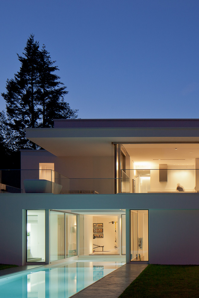 Réalisation d'une façade de maison blanche minimaliste à un étage avec un toit plat.