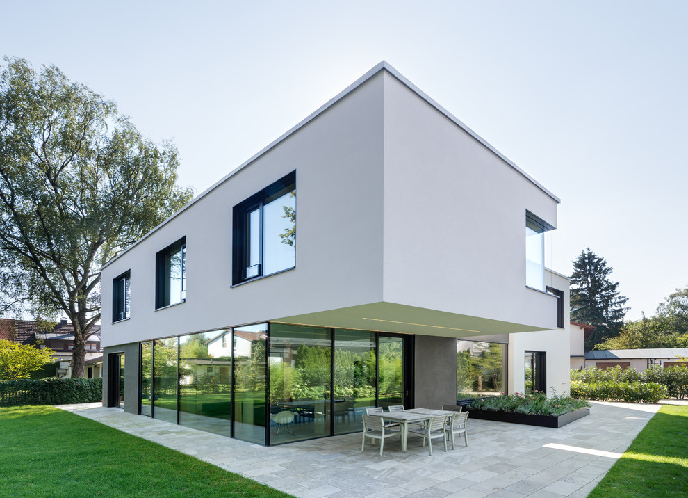 White and medium sized modern two floor house exterior in Munich with a flat roof.
