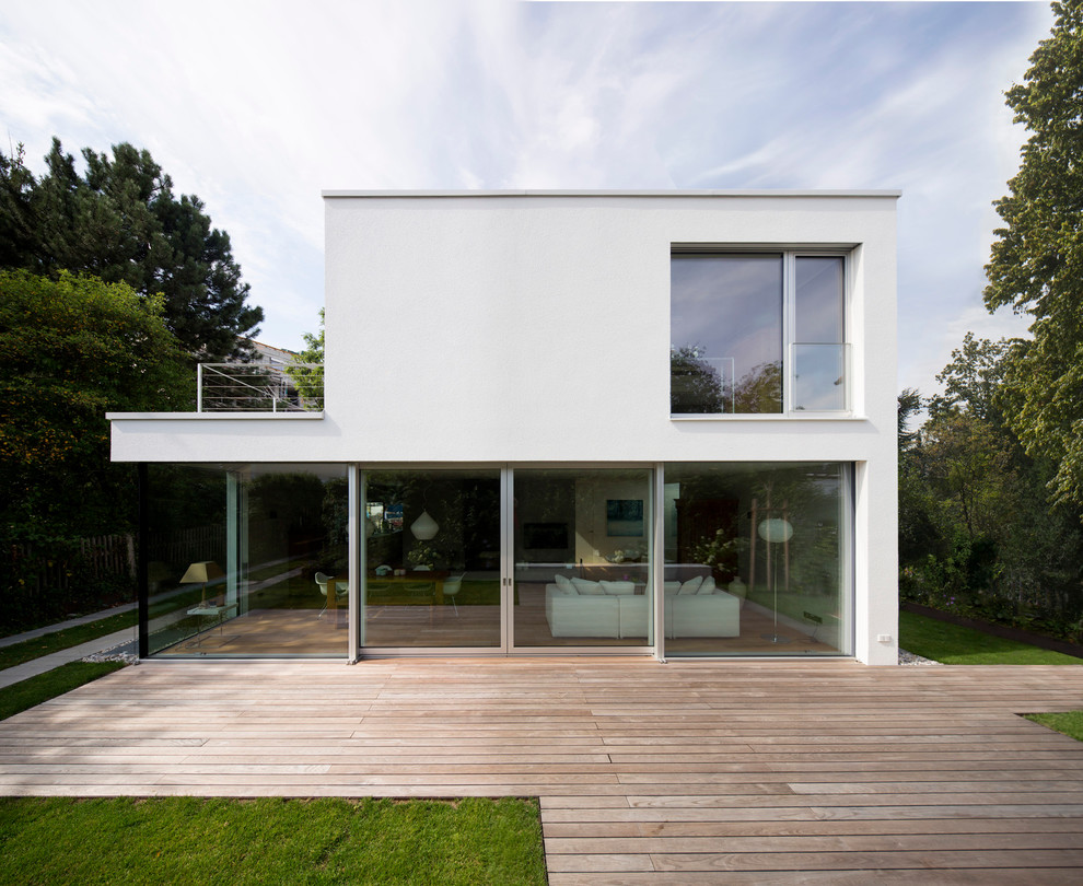 Photo of a large and white modern two floor concrete house exterior in Munich with a flat roof.