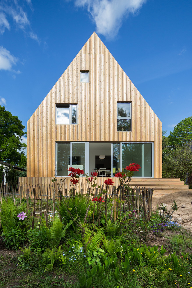 На фото: деревянный, коричневый, большой, трехэтажный дом в скандинавском стиле с двускатной крышей