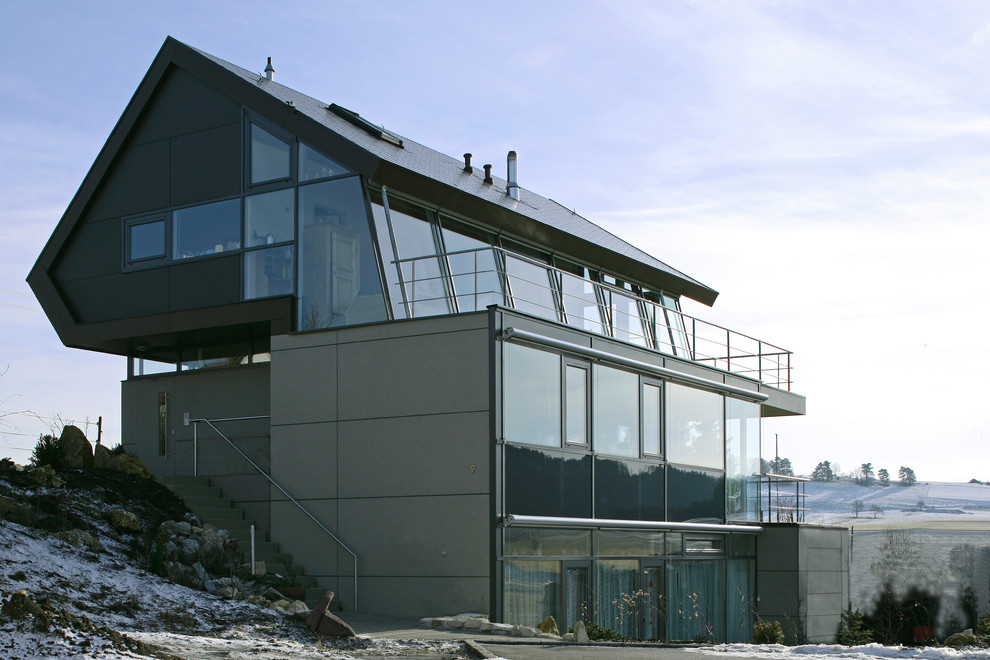 Diseño de fachada gris actual de tres plantas con tejado a dos aguas y revestimientos combinados