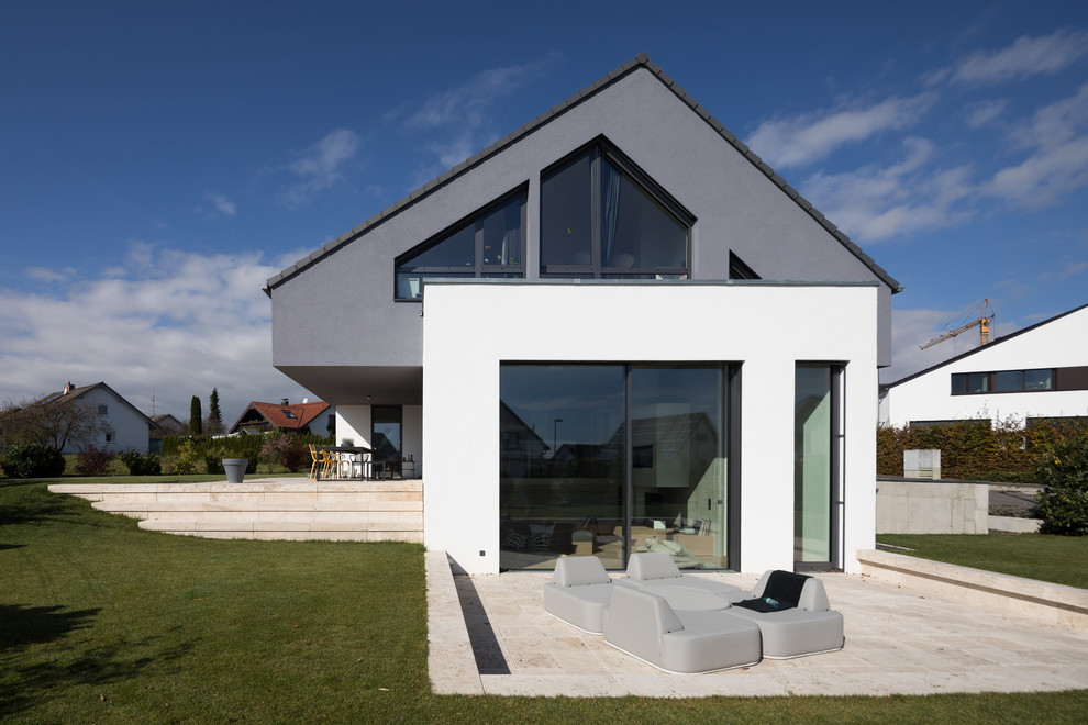 Стильный дизайн: серый частный загородный дом среднего размера в современном стиле с разными уровнями, облицовкой из цементной штукатурки, двускатной крышей и черепичной крышей - последний тренд