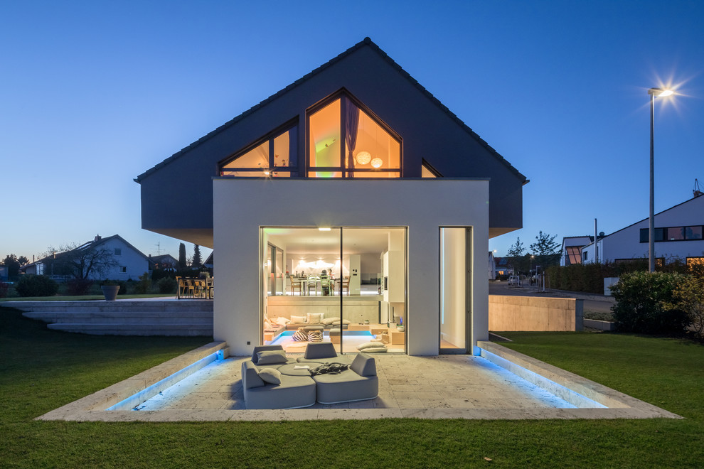 Imagen de fachada de casa gris contemporánea de tamaño medio a niveles con revestimiento de estuco, tejado a dos aguas y tejado de teja de barro