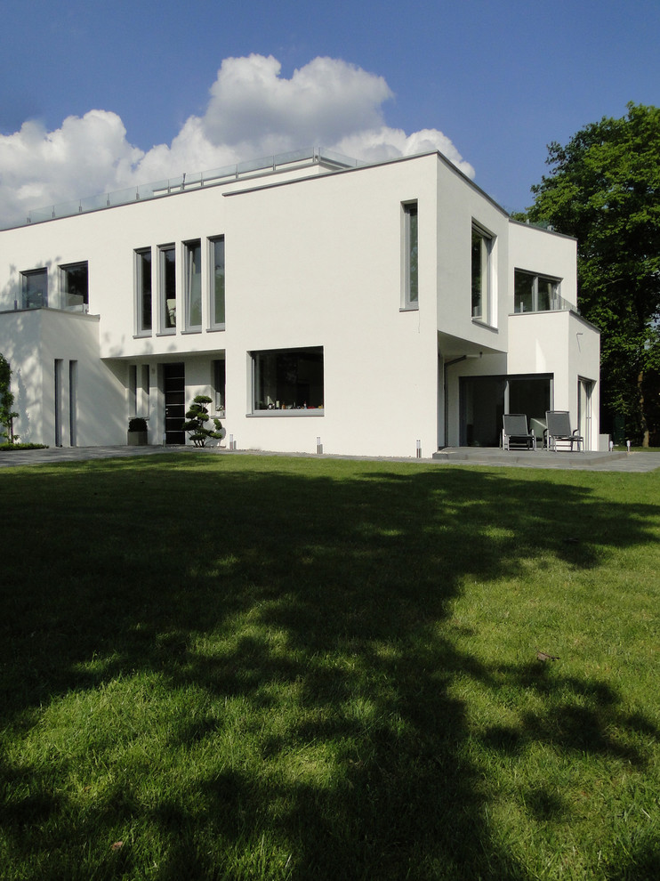 Свежая идея для дизайна: большой, двухэтажный, белый частный загородный дом в стиле модернизм с облицовкой из цементной штукатурки, плоской крышей и зеленой крышей - отличное фото интерьера
