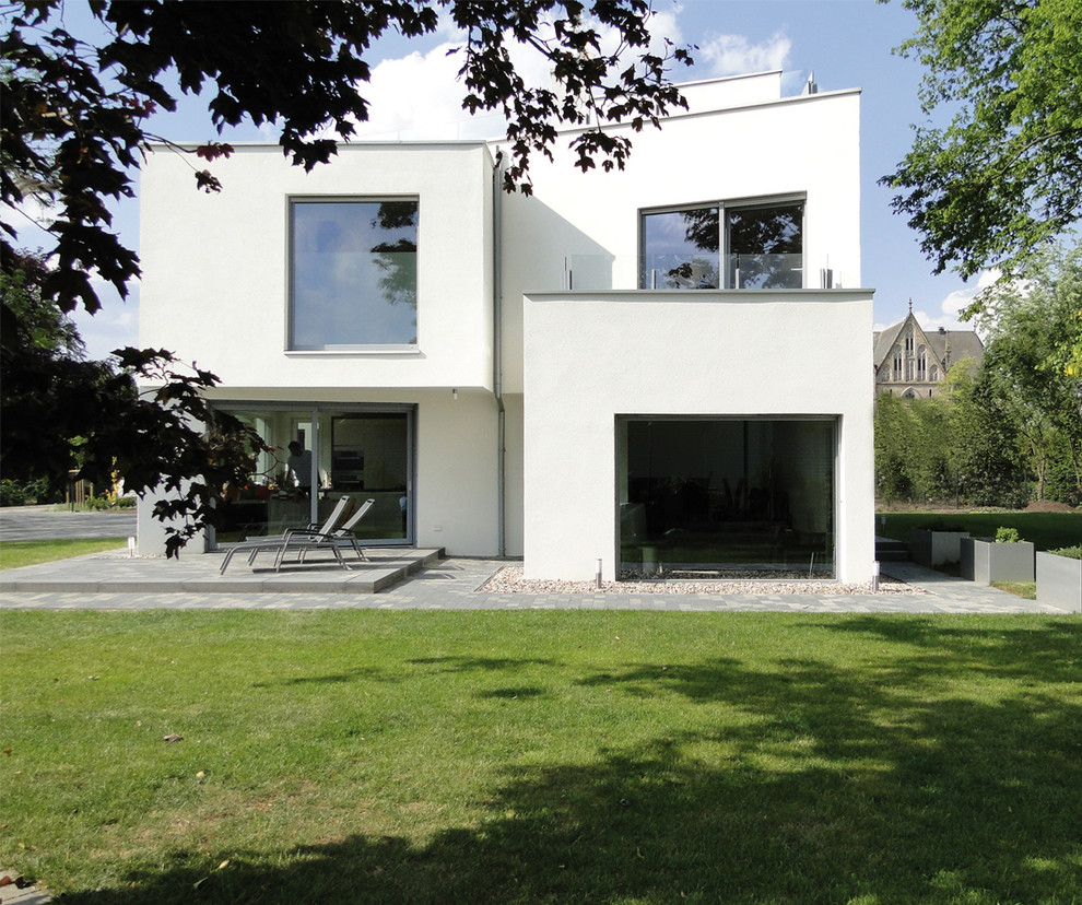 Large and white modern two floor render detached house in Bremen with a flat roof and a green roof.