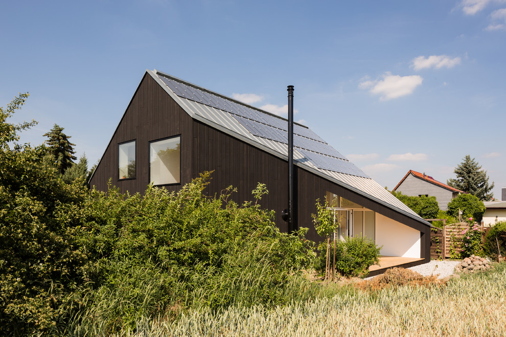Idées déco pour une façade de maison noire contemporaine en bois à un étage avec un toit à deux pans et un toit en métal.