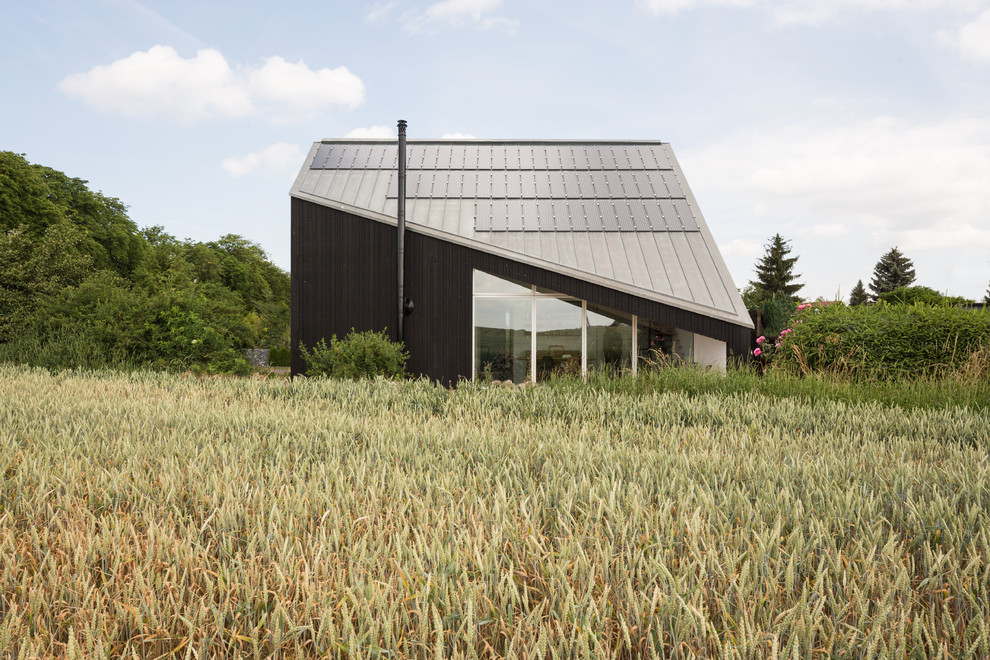 Diseño de fachada de casa negra contemporánea de dos plantas con revestimiento de madera, tejado a dos aguas y tejado de metal