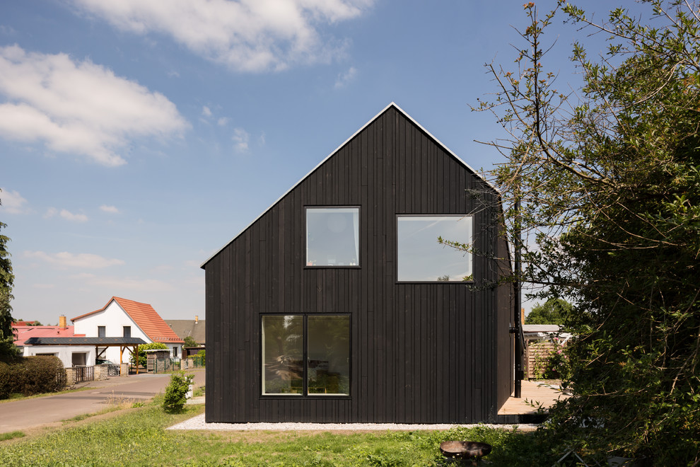 Ispirazione per la villa nera contemporanea a due piani con rivestimento in legno, tetto a capanna e copertura in metallo o lamiera