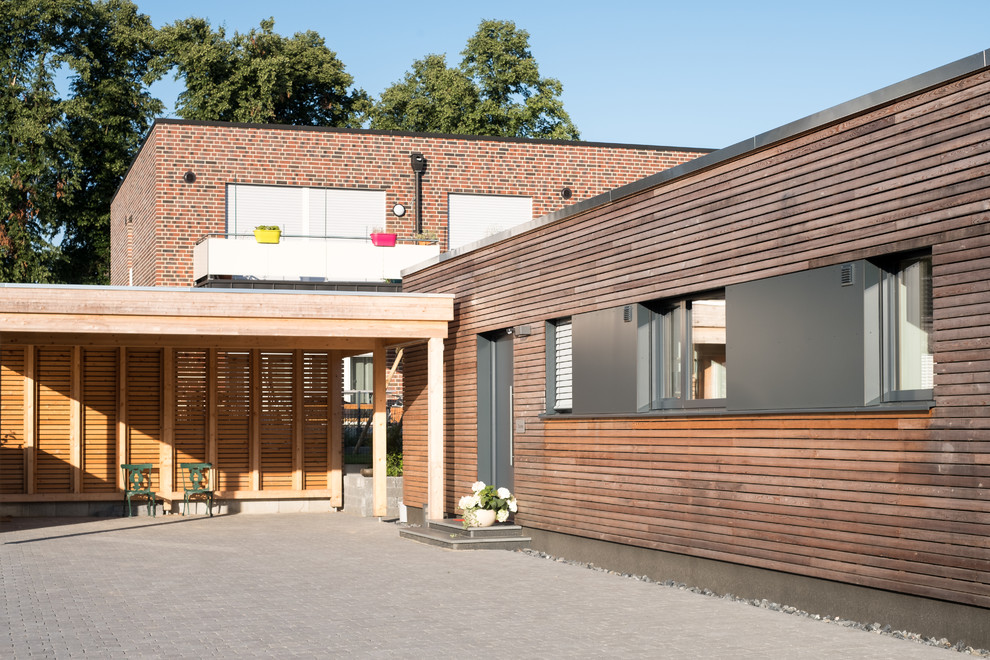 Cette image montre une très grande façade de maison minimaliste en bois et bardage à clin avec un toit plat.