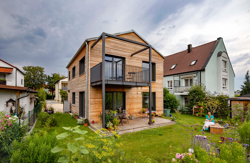Photo of a scandinavian two floor detached house in Munich with wood cladding, a pitched roof, a tiled roof, a grey roof and shiplap cladding.