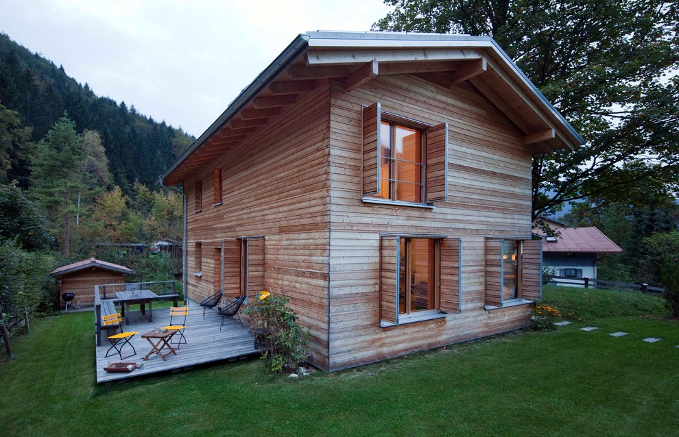 Modelo de fachada de casa marrón rural de tamaño medio de dos plantas con revestimiento de madera, tejado a dos aguas y tejado de teja de barro