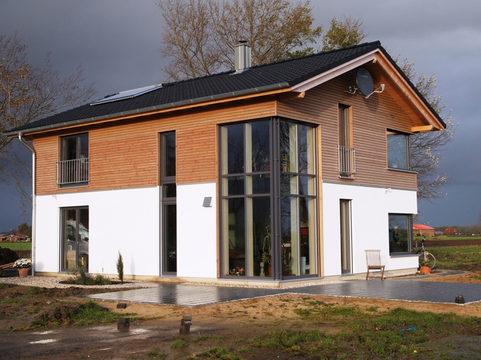 Réalisation d'une façade de maison marron design en bois de taille moyenne et à un étage avec un toit à deux pans et un toit en tuile.