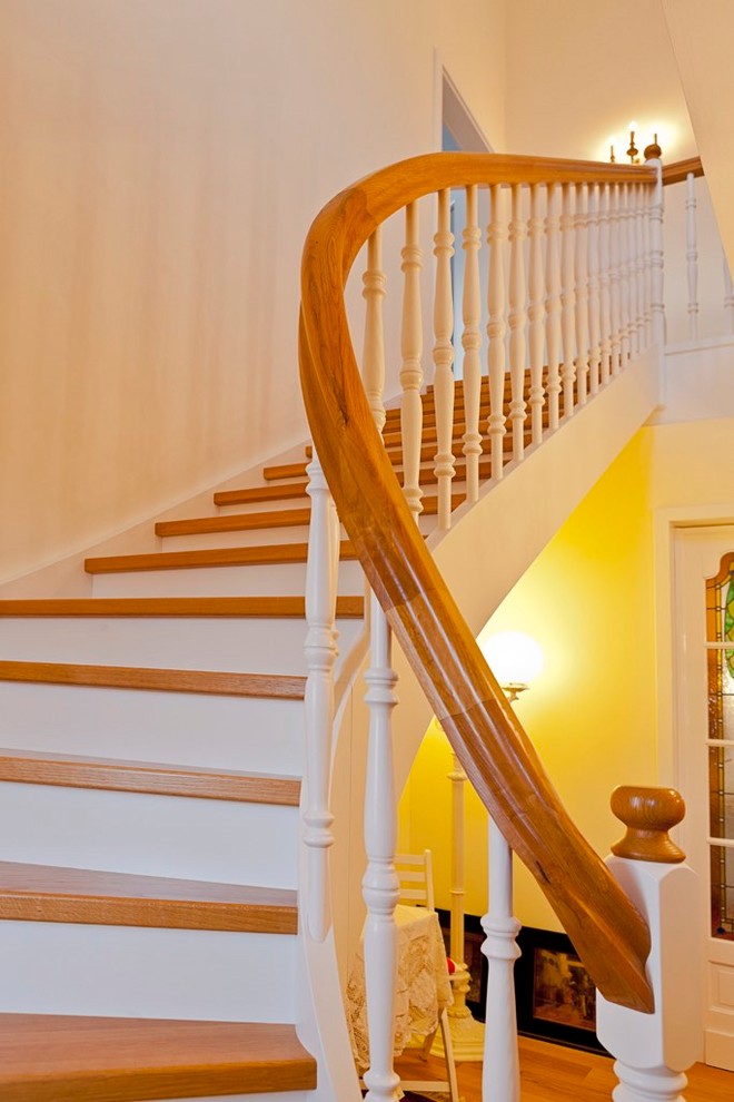 This is an example of a medium sized scandi wood curved wood railing staircase in Frankfurt with wood risers.