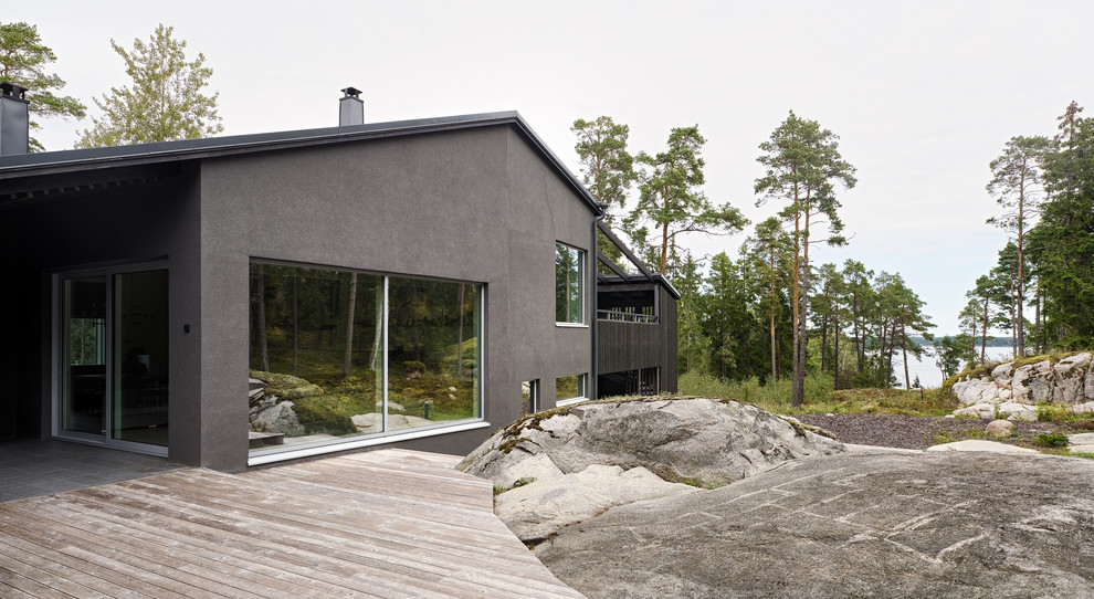 Стильный дизайн: серый дом среднего размера в скандинавском стиле с разными уровнями, облицовкой из цементной штукатурки и двускатной крышей - последний тренд