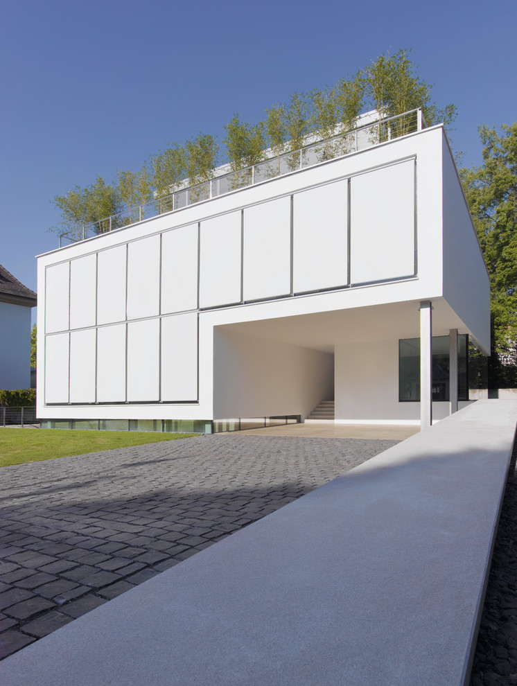 Modelo de fachada blanca actual grande de dos plantas con revestimiento de hormigón y tejado plano