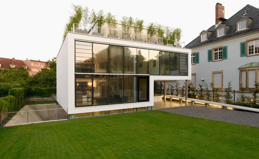 На фото: большой, белый, двухэтажный дом в современном стиле с плоской крышей
