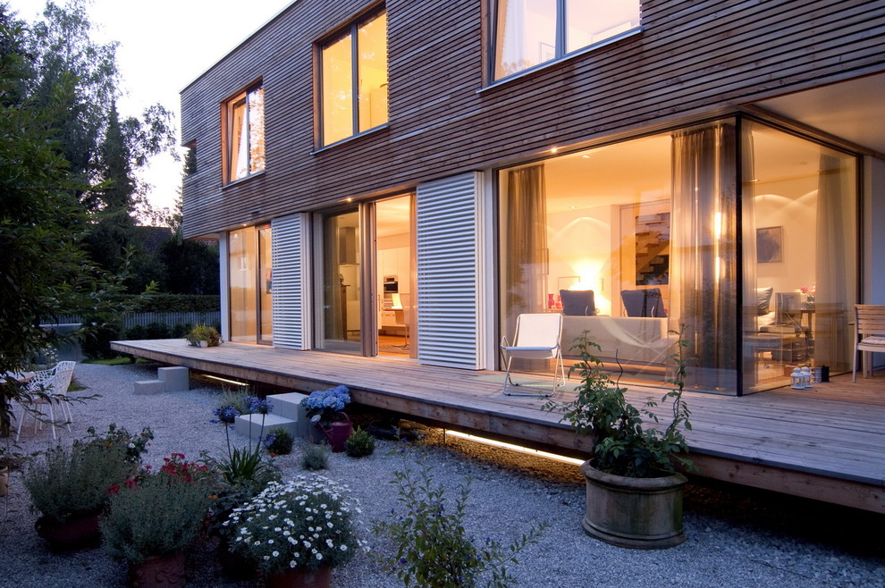 Modelo de fachada contemporánea de tamaño medio de dos plantas con revestimiento de madera y tejado plano