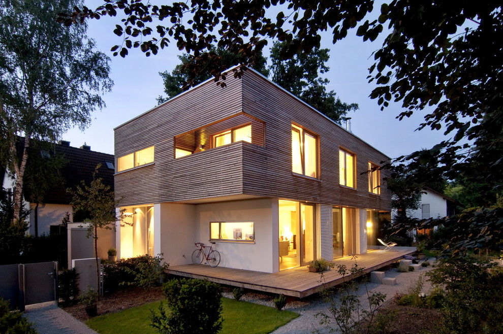 Design ideas for a medium sized and white contemporary two floor house exterior in Munich with wood cladding and a flat roof.