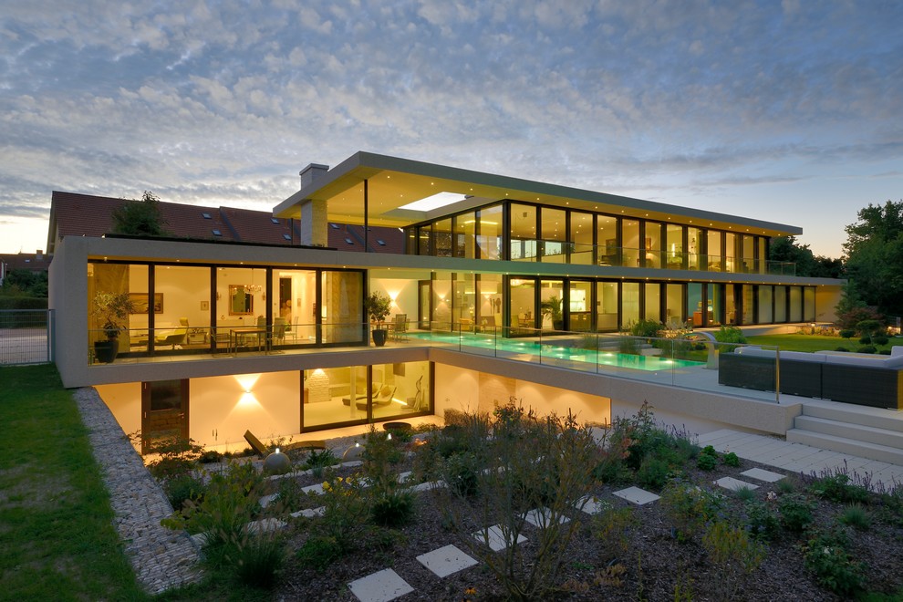 Foto della facciata di una casa grande contemporanea a tre piani con rivestimento in vetro e tetto piano