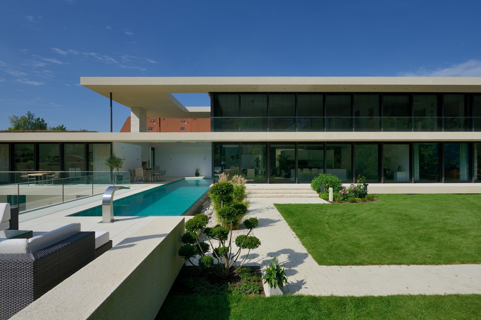 Foto på ett stort funkis hus, med tre eller fler plan, glasfasad och platt tak
