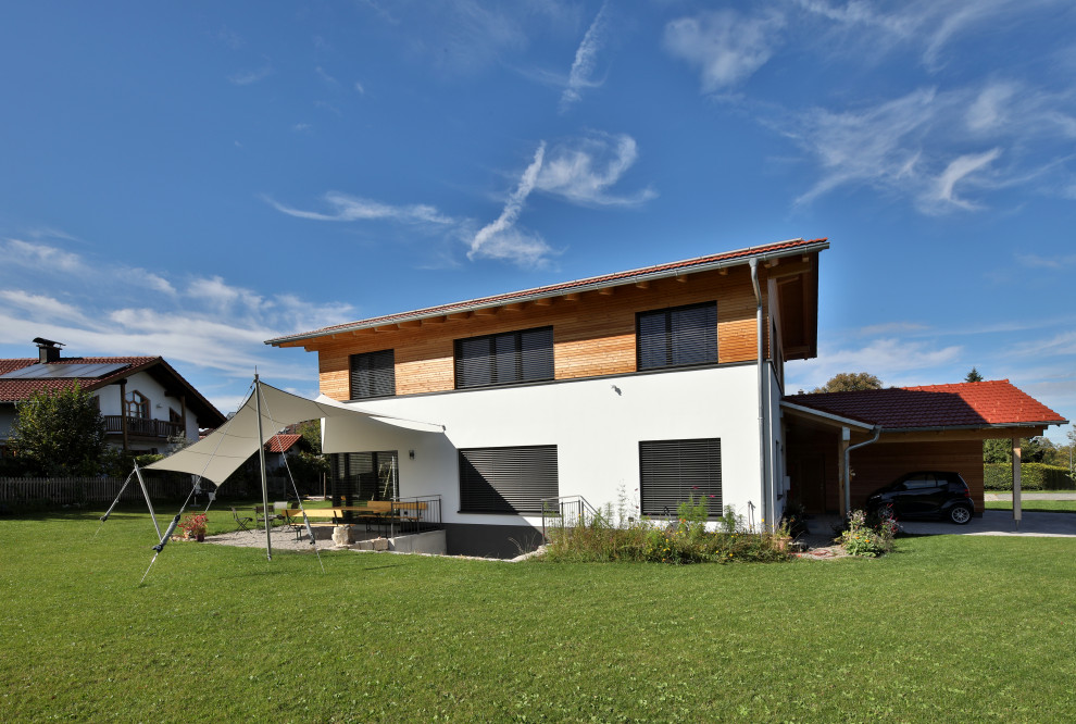Large trendy two-story wood exterior home photo in Munich with a tile roof