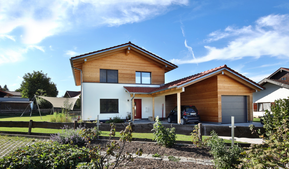 Ejemplo de fachada de casa contemporánea grande de dos plantas con revestimiento de madera, tejado a dos aguas y tejado de teja de barro