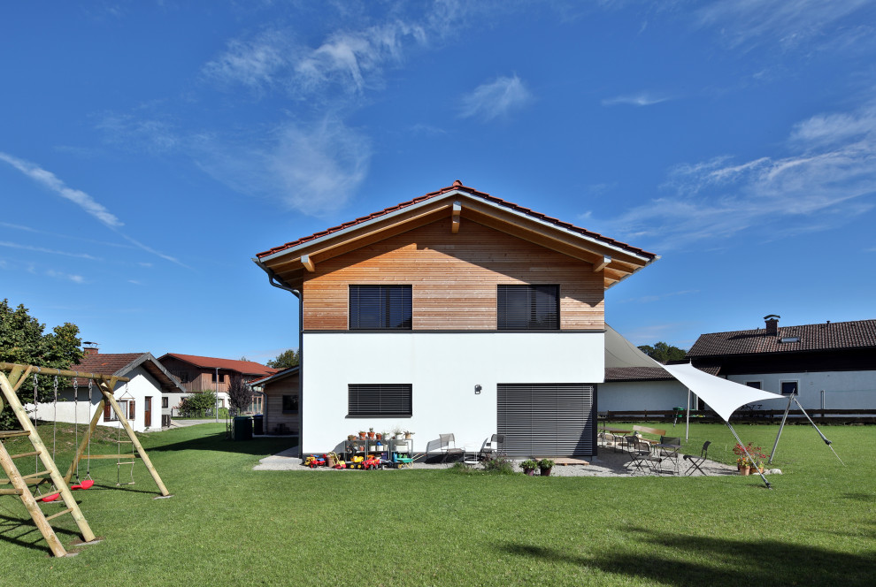 Réalisation d'une grande façade de maison design en bois à un étage avec un toit à deux pans et un toit en tuile.