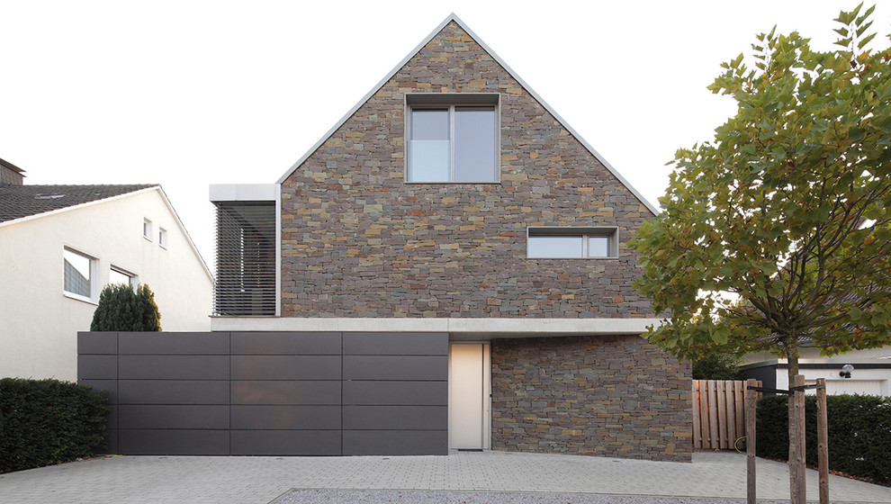 Photo of a medium sized contemporary brick house exterior in Other with three floors and a pitched roof.