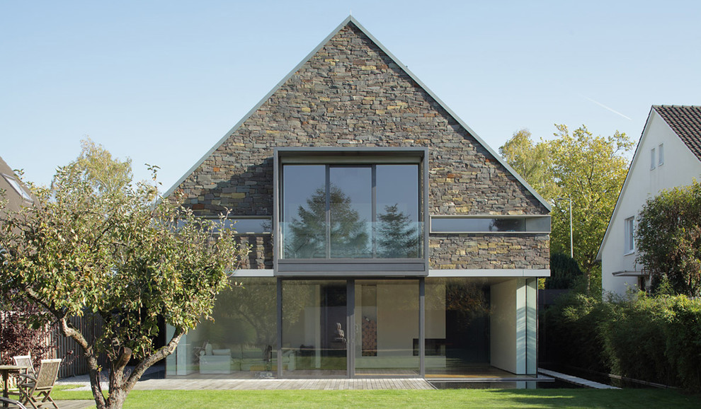 Réalisation d'une façade de maison design en pierre de taille moyenne et à un étage avec un toit à deux pans.